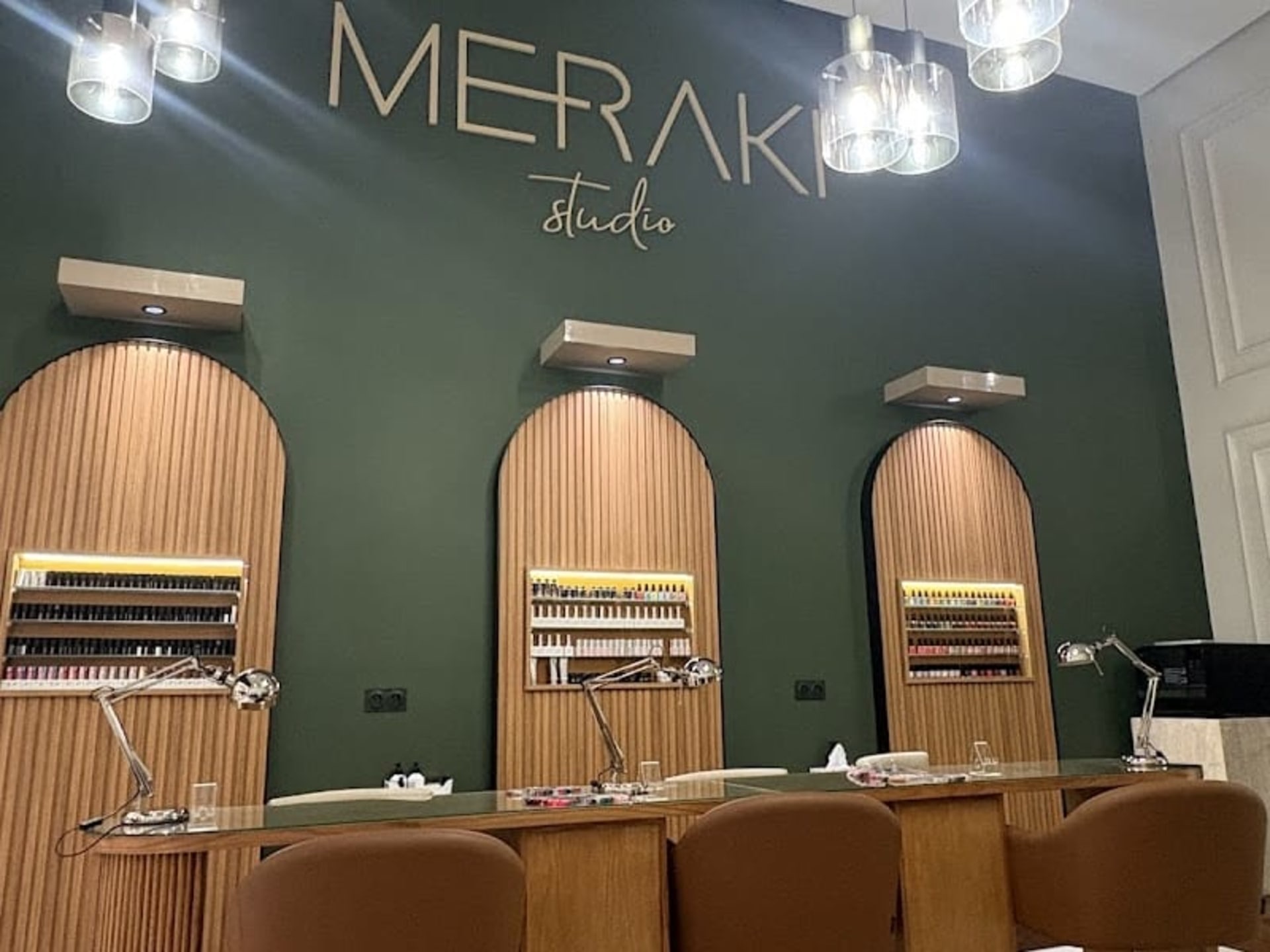 Logo doré « Meraki studio » et espace onglerie aux arches cannelées